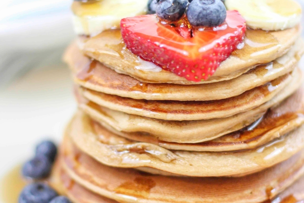 An indulgent Christmas breakfast recipe featuring a stack of pancakes topped with plump berries and drizzled with syrup.