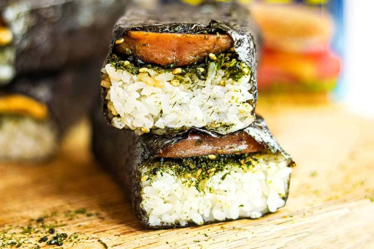 A stack of Hawaiian inspired sushi rolls on a cutting board.