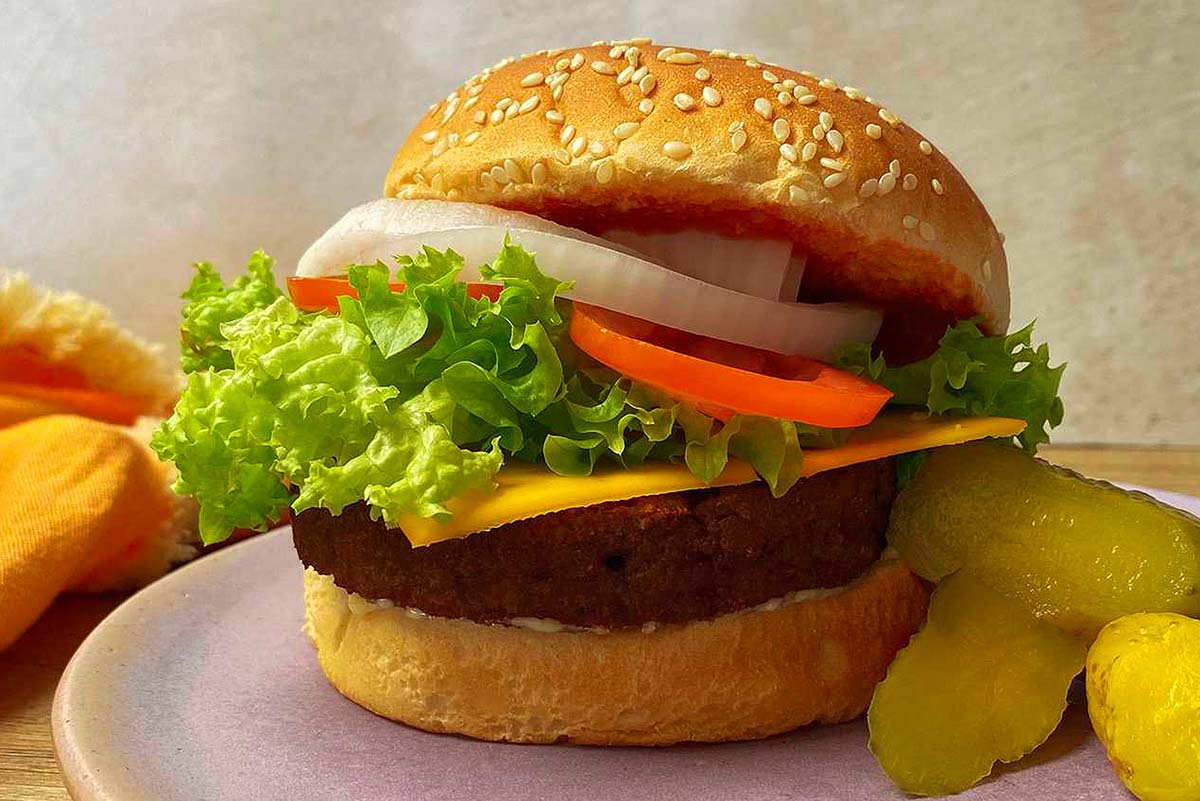 A burger with lettuce and pickles on a plate.
