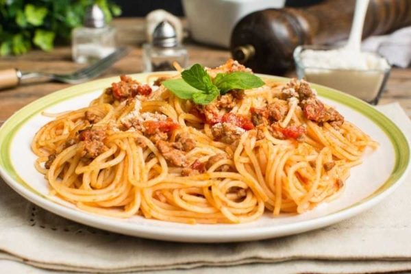 Spaghetti with meat and tomatoes on a plate.