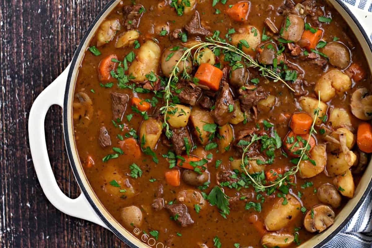 A comforting winter dinner of Irish beef stew sizzling in a pan on a table.