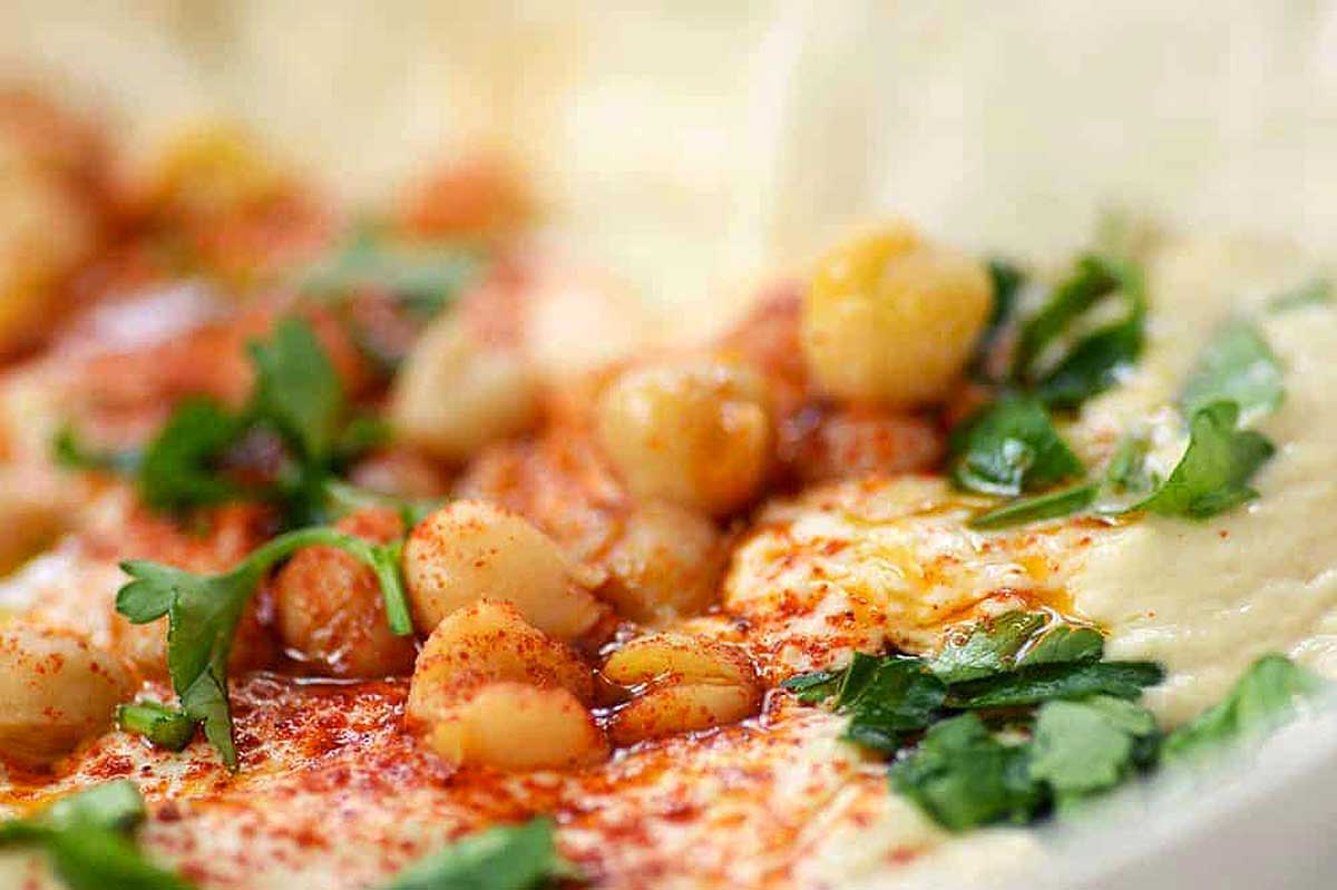 A bowl of hummus with chickpeas and parsley, perfect for Instant Pot Thanksgiving.