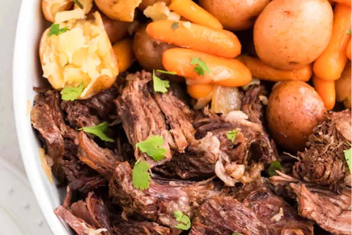 Slow cooker beef stew with carrots and potatoes in a white bowl.