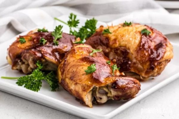 Bbq chicken thighs on a white plate with parsley.
