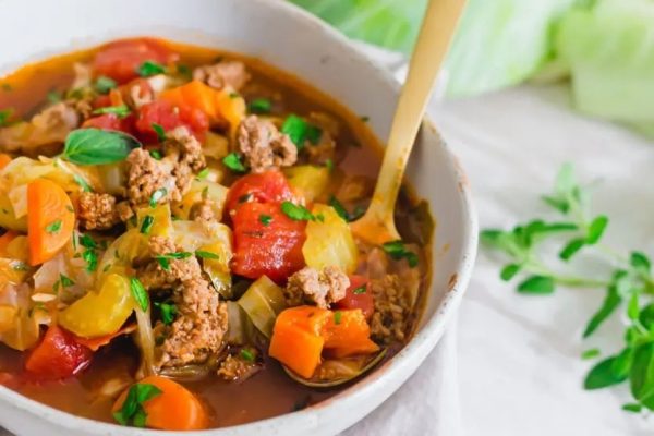 A bowl of cabbage soup with meat and vegetables.