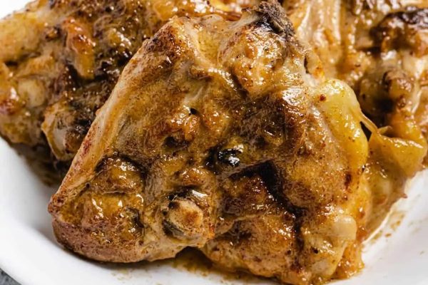 Chicken chops in a white bowl with sauce.