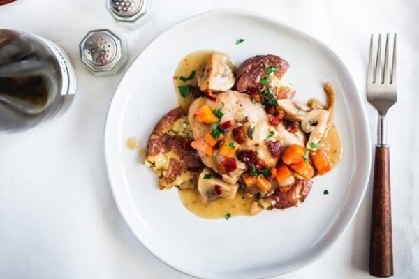 A white plate with mushrooms, carrots and gravy.