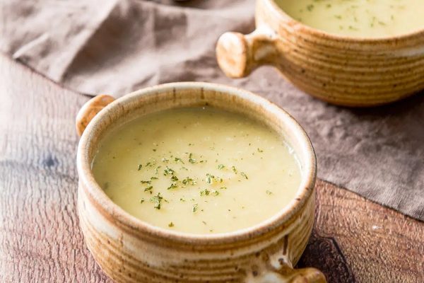 Two bowls of soup on a wooden table.