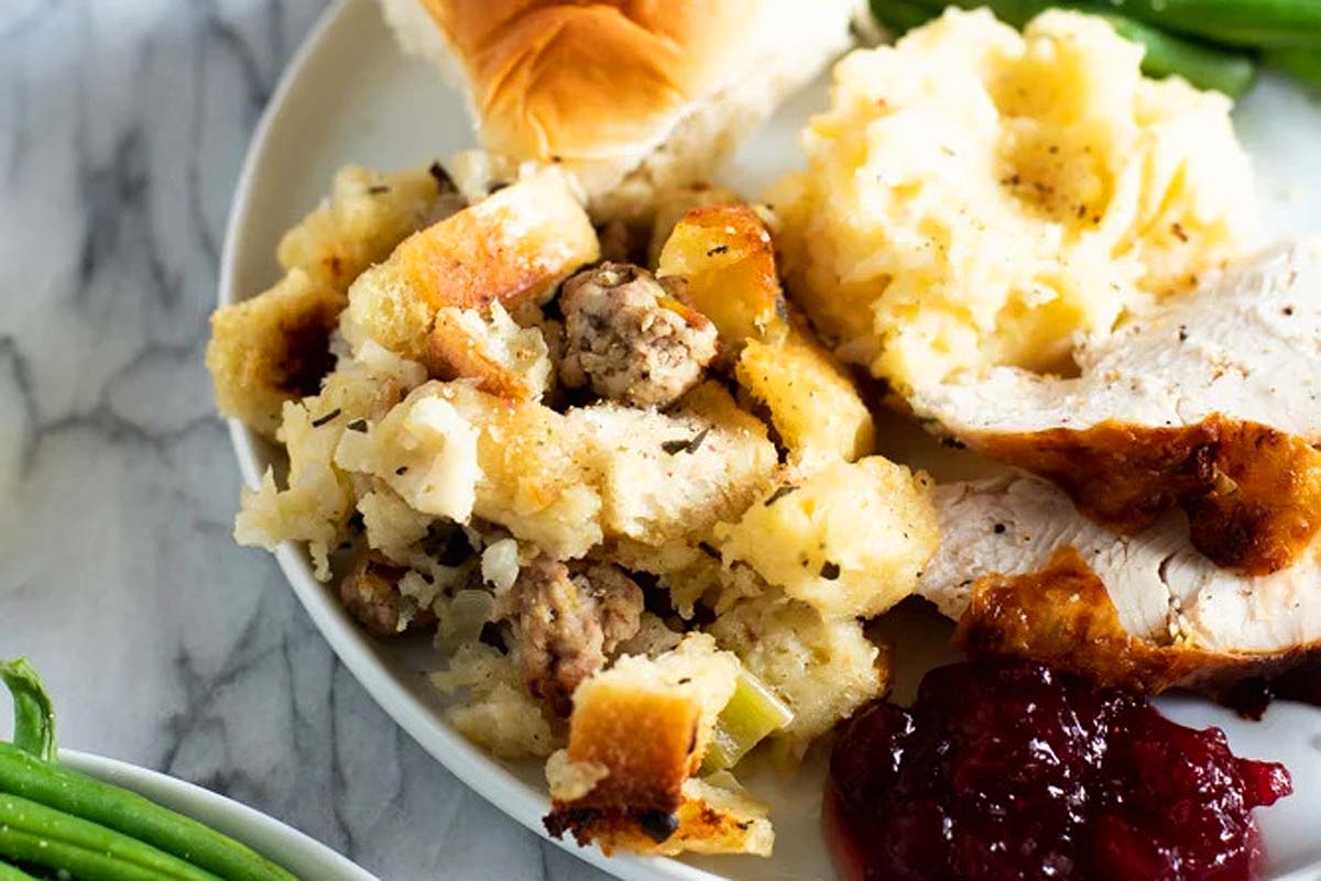 A plate with stuffing, green beans and cranberry sauce. This meal features a delicious combination of flavors, including a savory stuffing, crisp green beans and tangy cranberry sauce. 