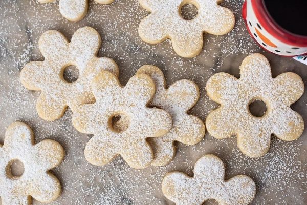 Sugar cookies with powdered sugar and a cup of coffee.