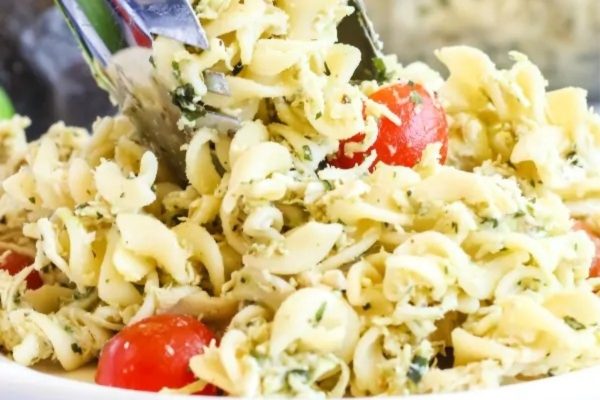 A bowl of pasta salad with tomatoes and basil.