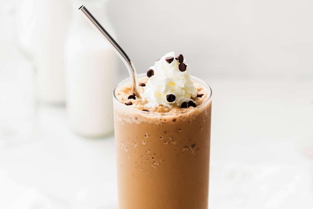 A Starbucks chocolate milkshake with whipped cream and a straw.