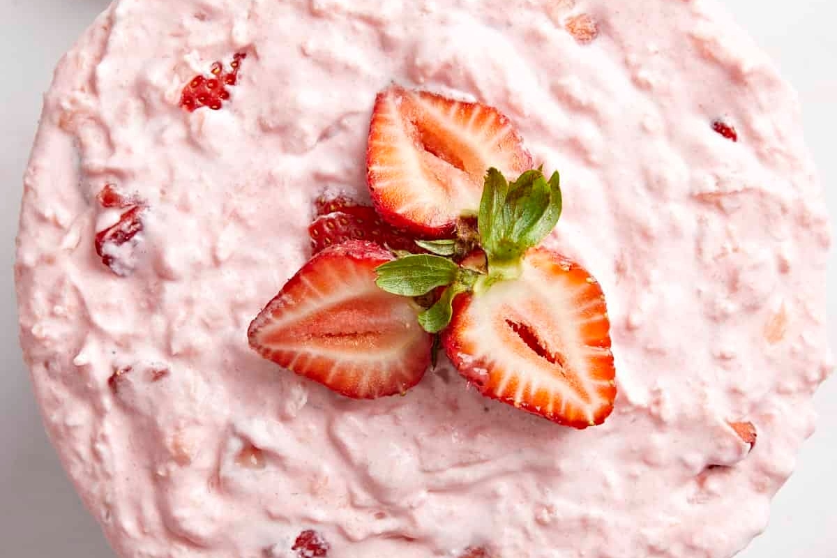 A delicious bowl of strawberry ice cream garnished with fresh strawberries.
