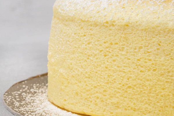 A close up of a yellow cake with powdered sugar.