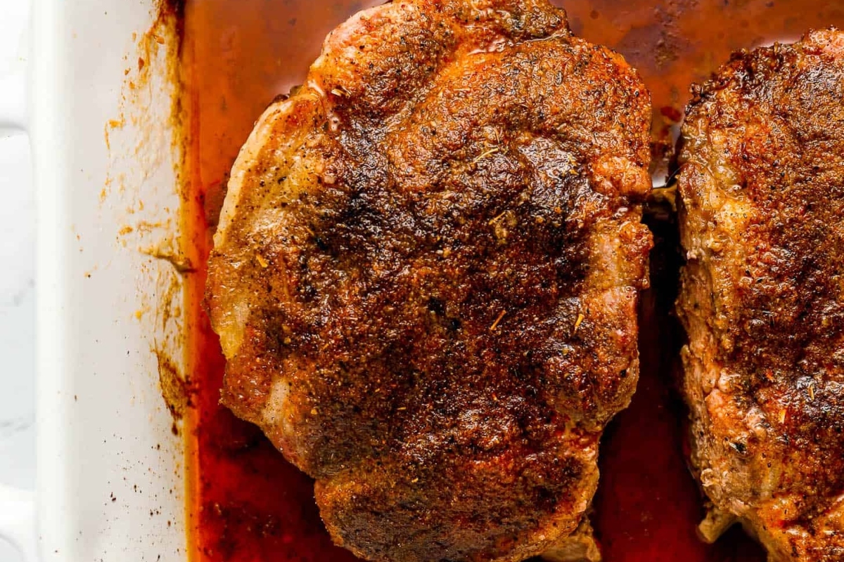 Two succulent pork chops in a baking dish.