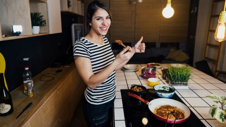 A woman in a striped shirt is preparing food in the kitchen.