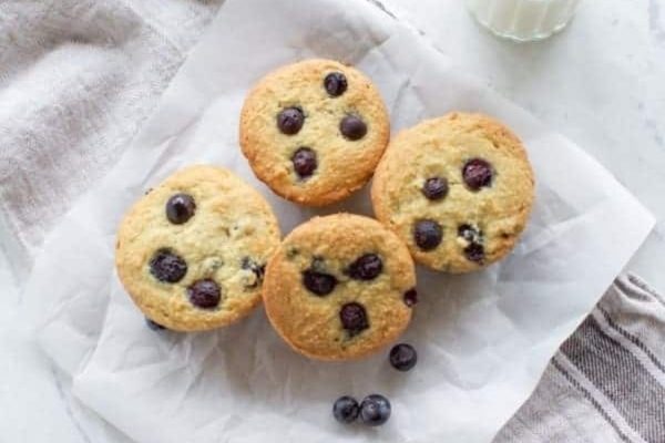 Blueberry muffins on a napkin with a glass of milk for breakfast.
