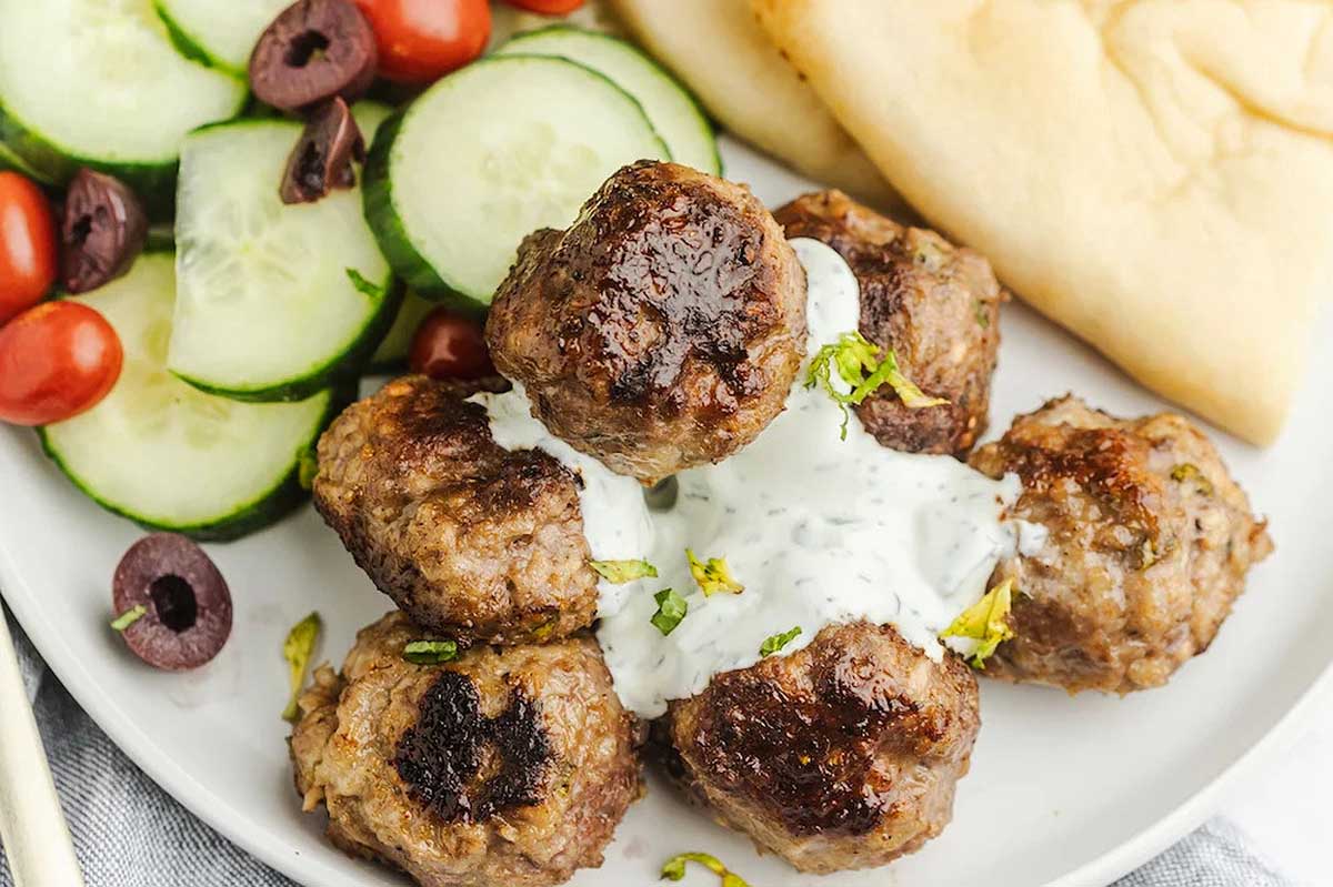 Gyro meatballs with tzatziki sauce on a plate.