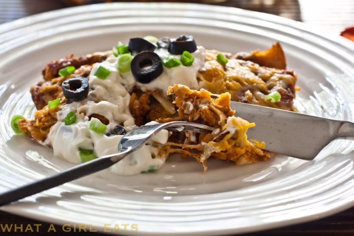 Leftover turkey enchilada with sour cream and olives on a plate.
