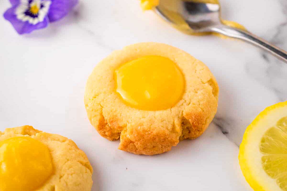 A lemon thumbprint cookie on a counter.