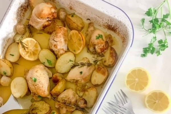 Chicken, potatoes and lemons in a baking dish.