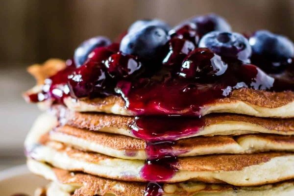 A stack of pancakes with blueberry sauce on top.