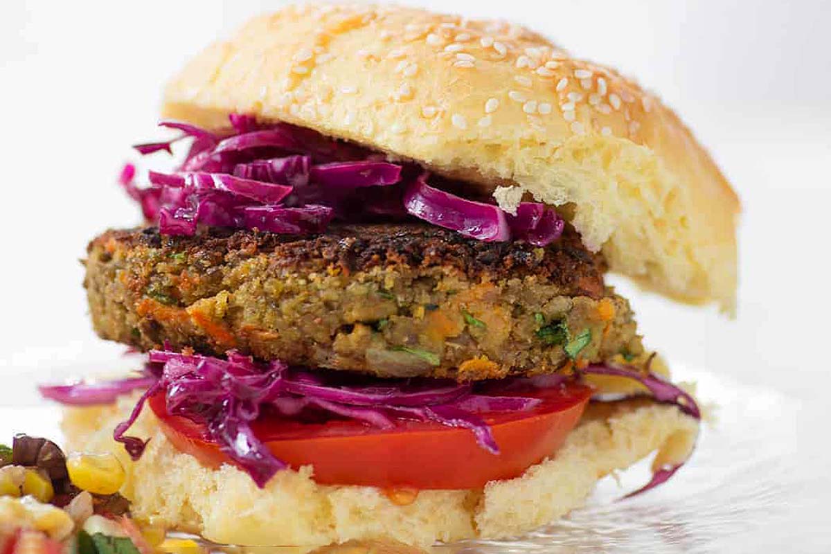 A burger with slaw and coleslaw on a plate.