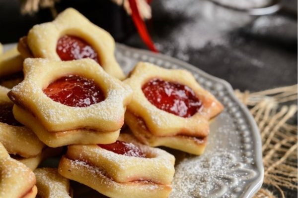 Star shaped cookies with jam and powdered sugar on a plate.