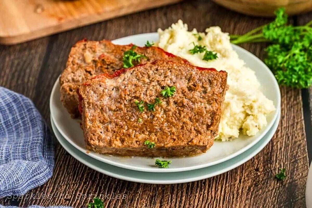 Mouthwatering meatloaf recipe served with creamy mashed potatoes and a sprinkle of fresh parsley.