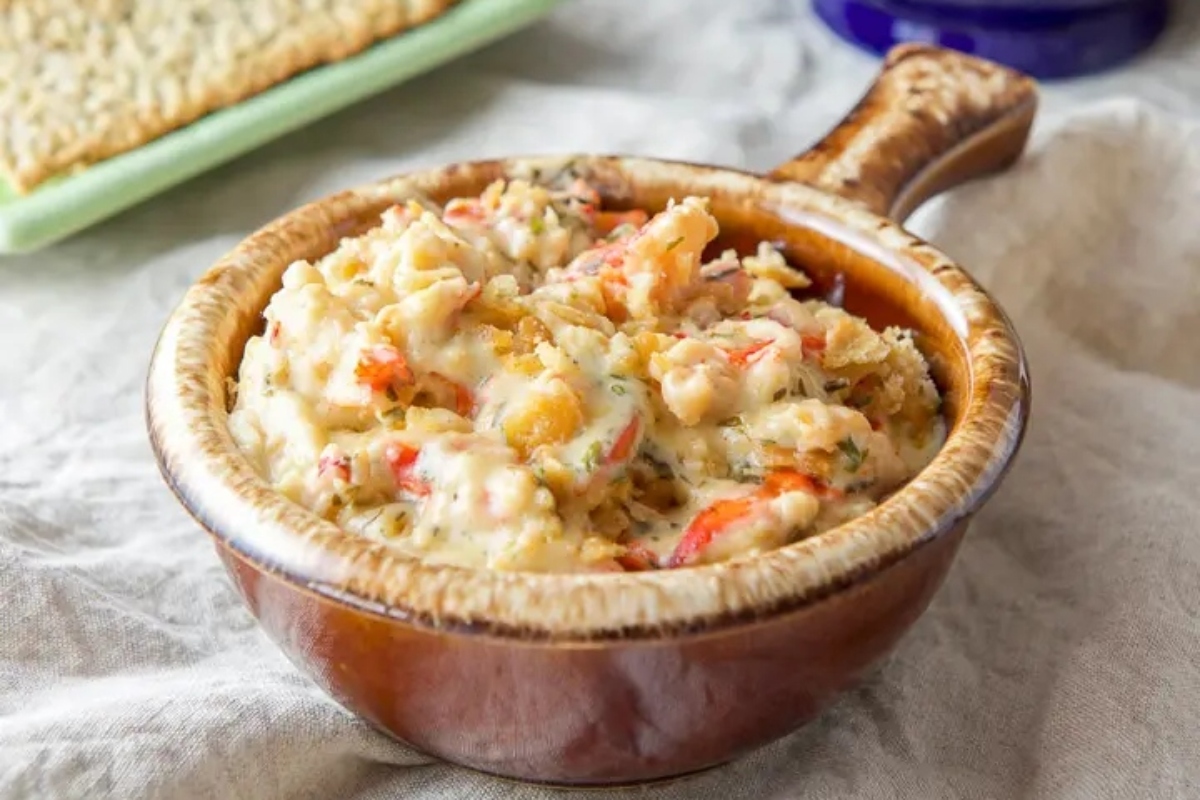 A bowl of dip with crackers next to it.