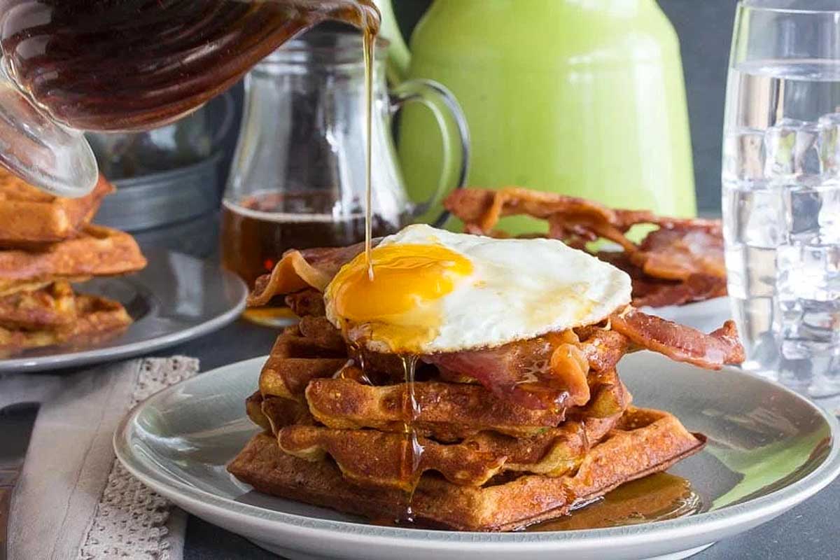 A stack of waffles with an egg on top.