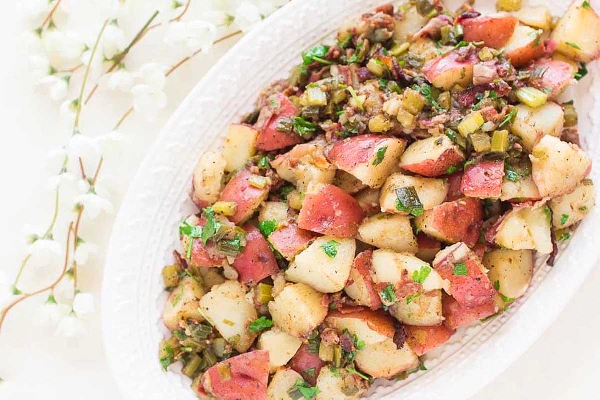 A white plate with potatoes and greens on it.