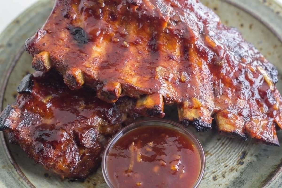 Mouthwatering BBQ ribs recipe smothered in savory sauce served on a plate.
