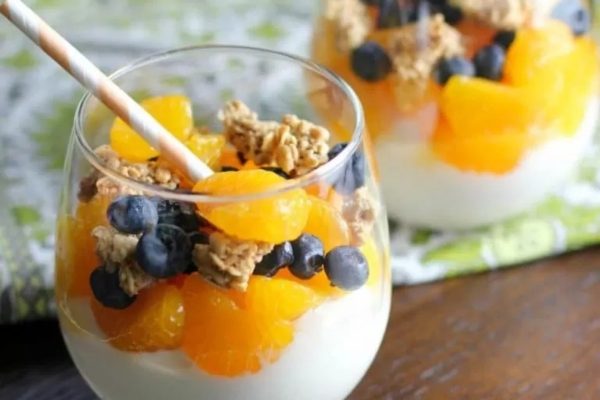 A refreshing glass of yogurt topped with juicy oranges and a sprinkle of crunchy granola.
