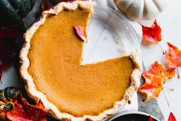 A pumpkin pie with a slice taken out.