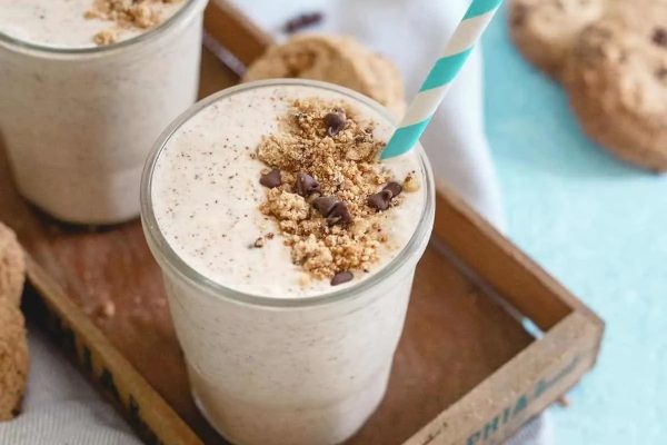 Two glasses of chocolate chip cookie smoothie milkshake on a tray.