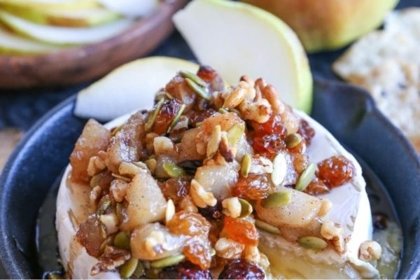 A plate of cheese with apples and nuts on it.