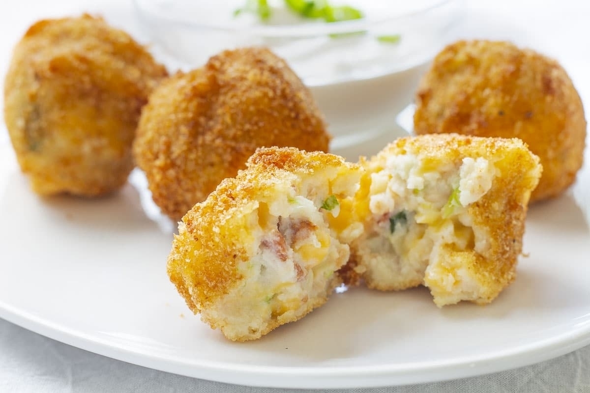 Mashed potato bites with sour cream on a white plate.