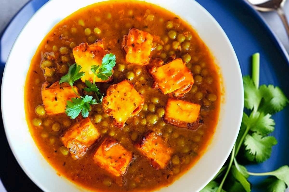 A bowl of tofu and frozen peas on a blue plate.