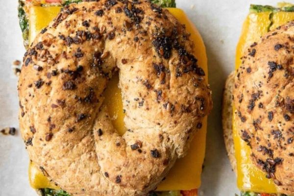 Three bagels with spinach and cheese on them.