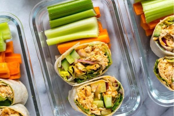 A tray of meal prep lunches with wraps, carrots, and celery.