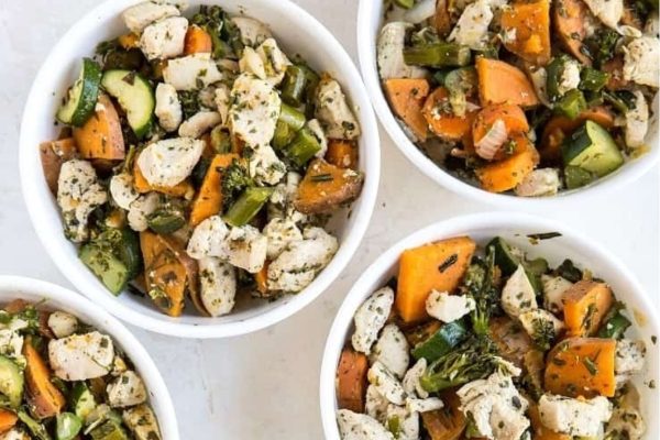Four white bowls filled with chicken and vegetables.