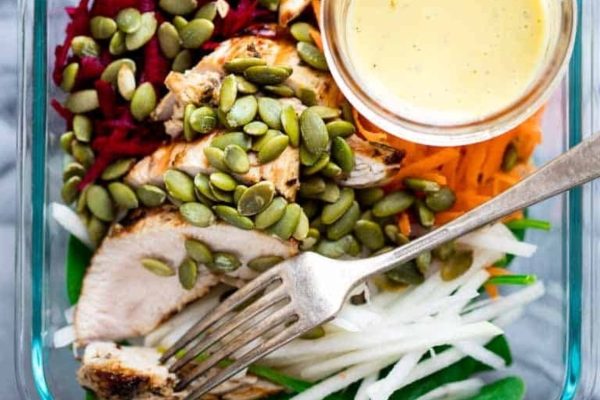 Meal prep: A salad with chicken and vegetables in a clear container with a fork, perfect for preparing lunches ahead of time.