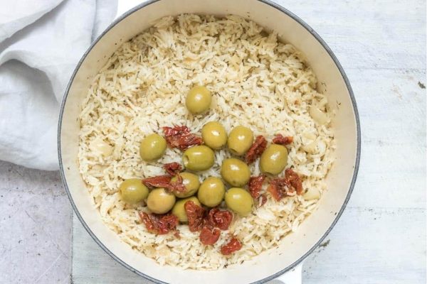 A delicious recipe for rice cooked with pantry staples such as olives and tomatoes in a pan.