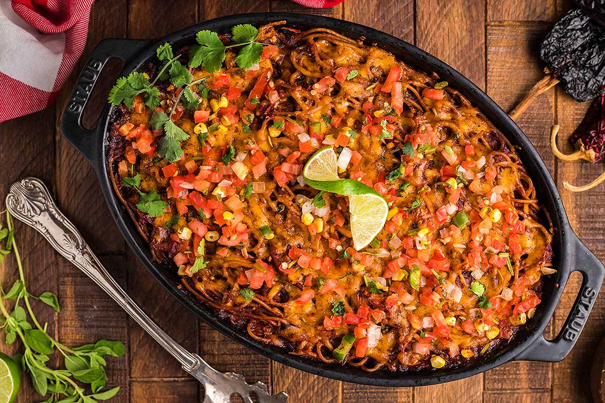 Mexican lasagna in a skillet on a wooden table.