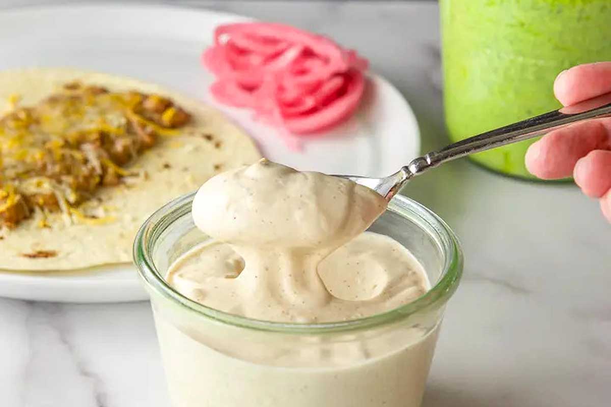 A person dipping a spoon into a jar of guacamole.