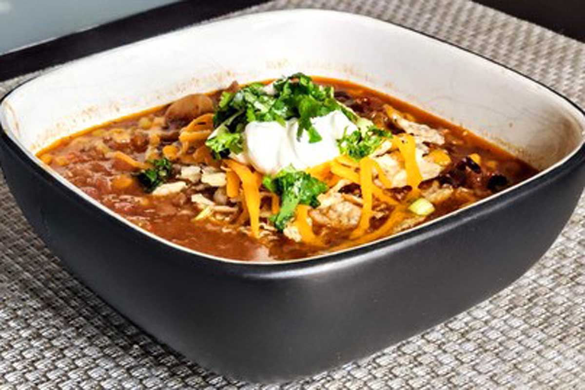 A bowl of chili with cheese and sour cream.