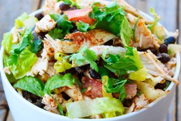 Mexican chicken salad in a bowl on a wooden table.