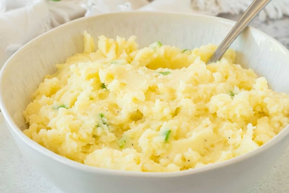 Mashed potatoes served in a white bowl with a spoon.