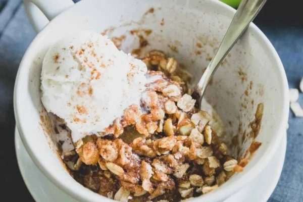 Apple crisp in a mug with ice cream and granola.